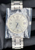 A Grand Seiko stainless steel wristwatch with a silver dial and metal bracelet, still sealed in clear protective plastic wrap.
